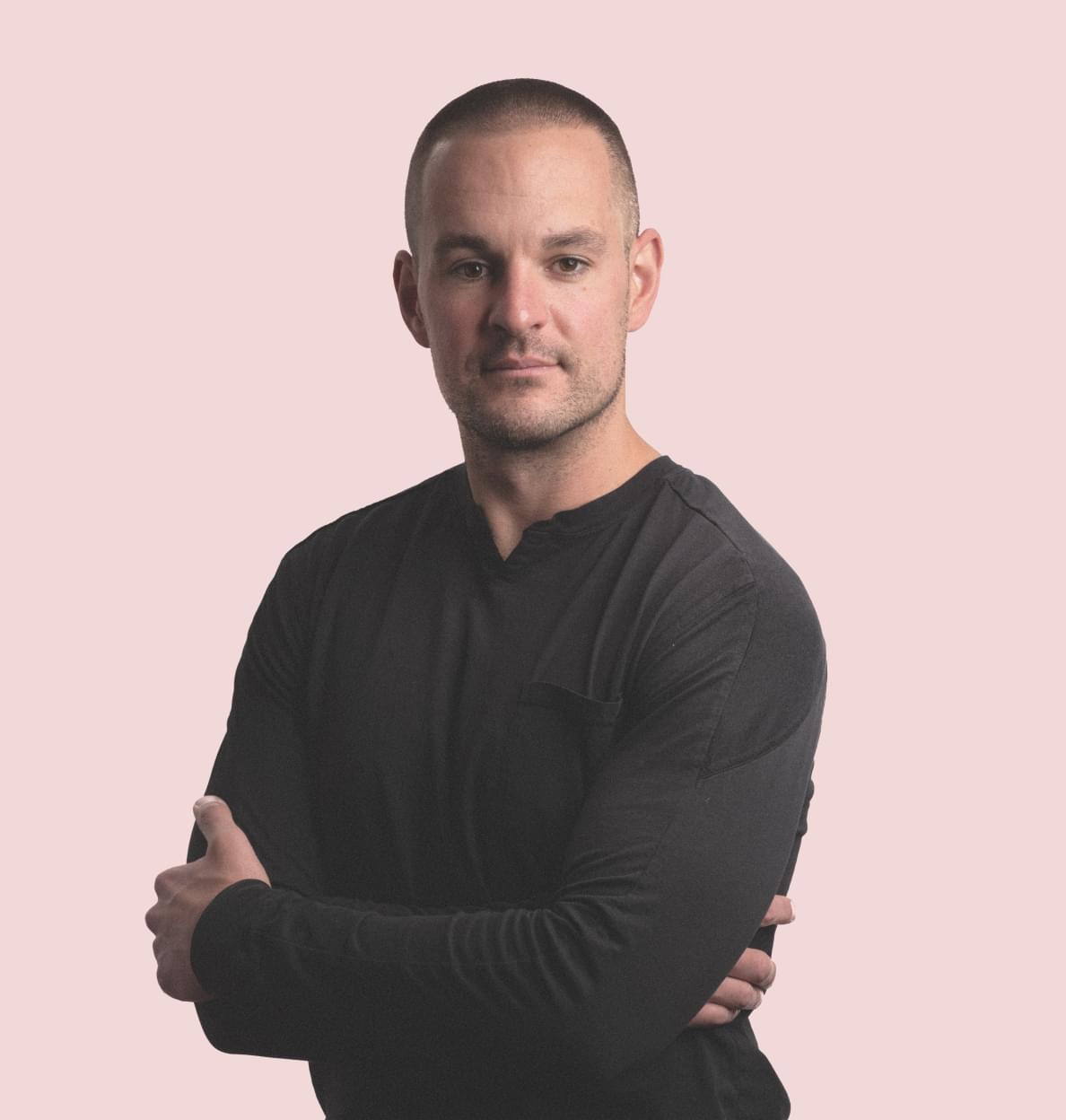 A portrait of Roger Dickerman on a pastel pink background.